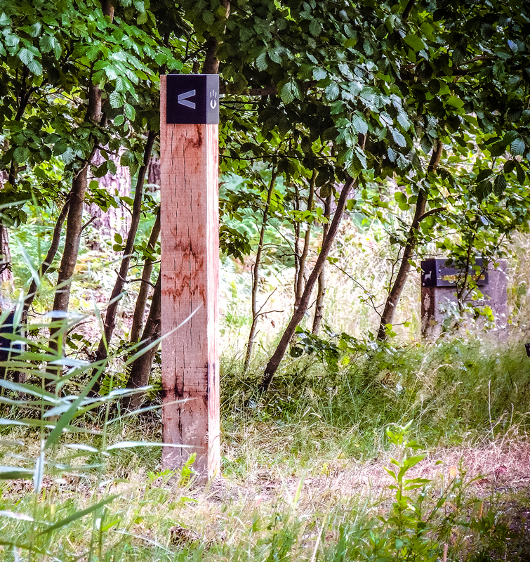 Houten paal in een natuurgebied met bewegwijzering erop