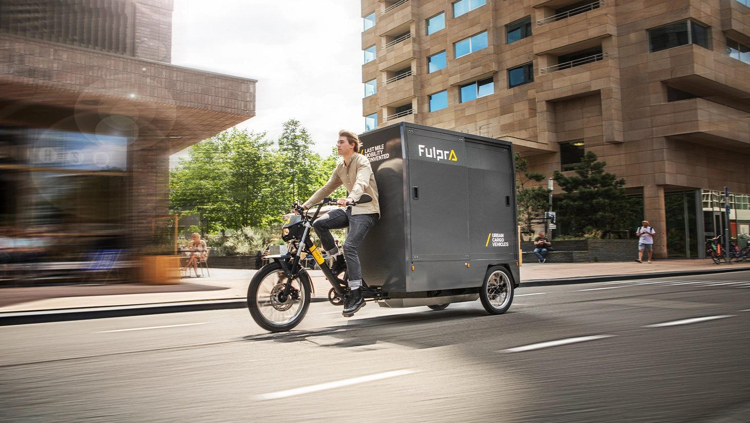 Man fietst op de Fulpra vrachtfiets door een straat met twee gebouwen