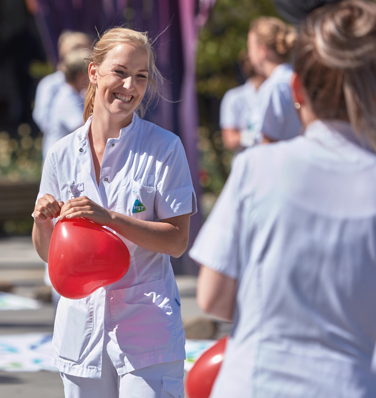 Twee medewerkers van het MST waarvan er één lacht en beide met een rode hartjes ballon in hun hand